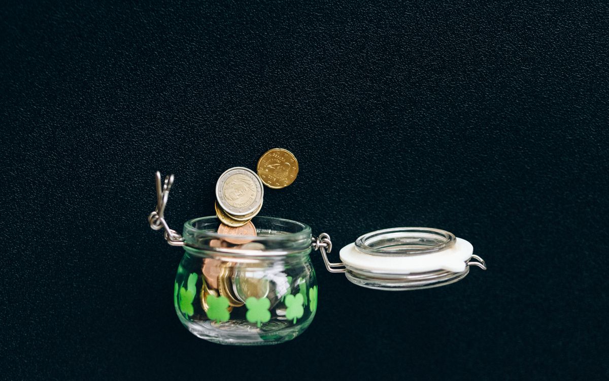 Munten vallen in een glazen spaarpot